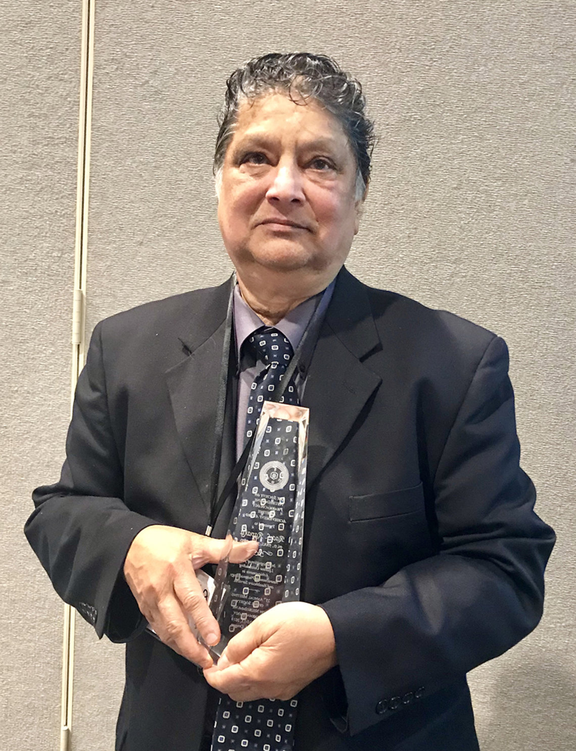 Dr. Rapaka holds up his award