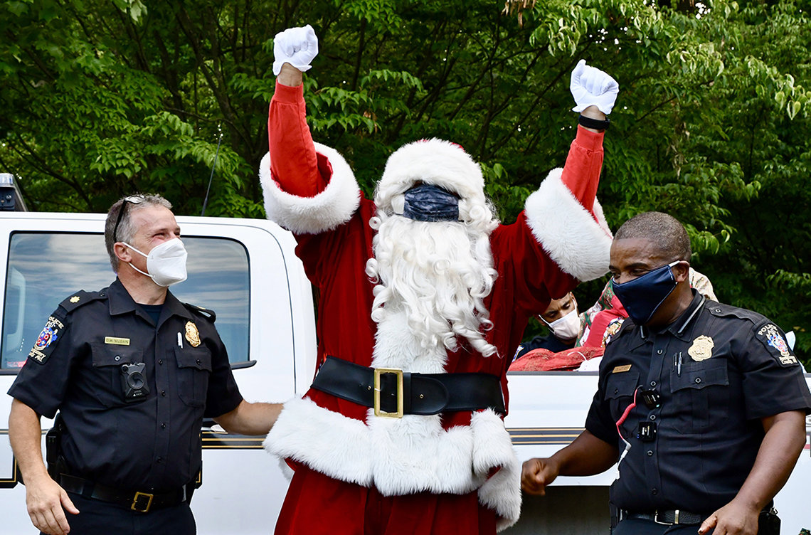 A masked Santa raises both arms in the air. 