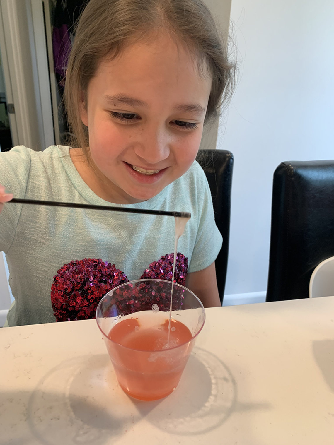 Soper pulls strawberry DNA up out of a clear, plastic cup using a coffee stirrer