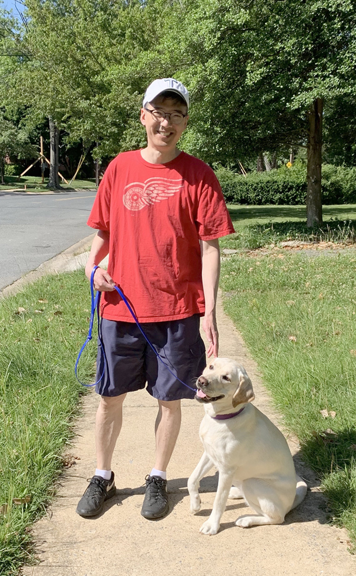 Chiang in shorts and T shirt with dog on leash