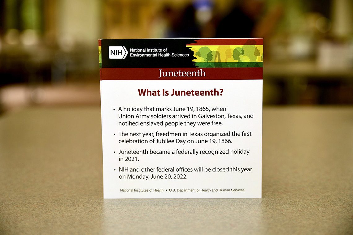 On a cafe table, a tent card announces the NIEHS Juneteenth event