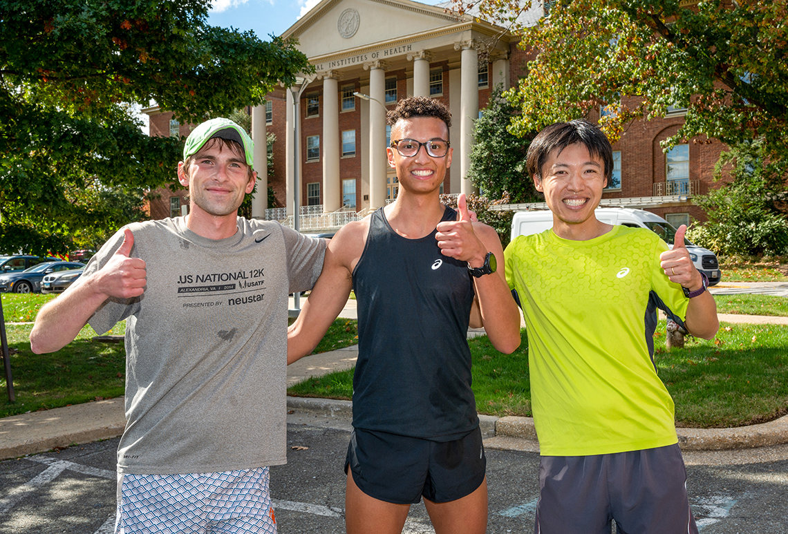 Three smiling, sweaty guys pose together after the race outside Bldg. 1.