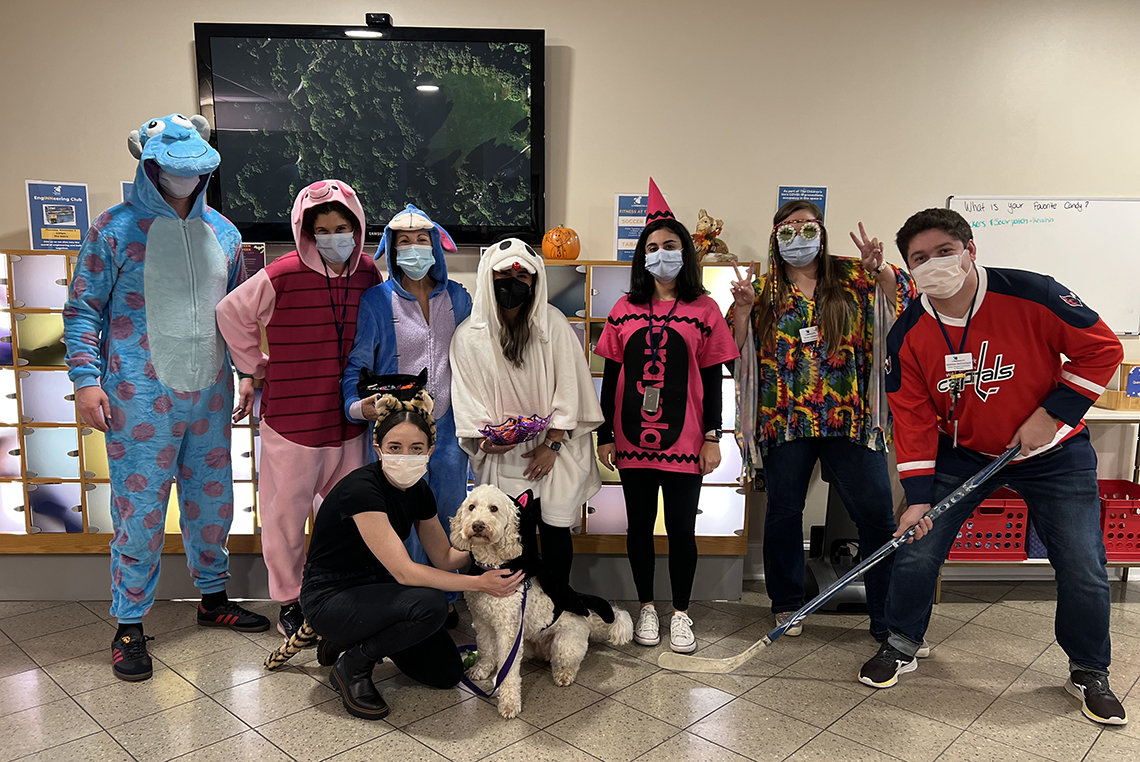 A group of NIH staff in costumes pose with Zilly at the Children's Inn.