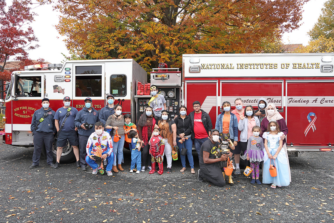 Large group of individuals, some in costumes, in front of an NIH fire engine