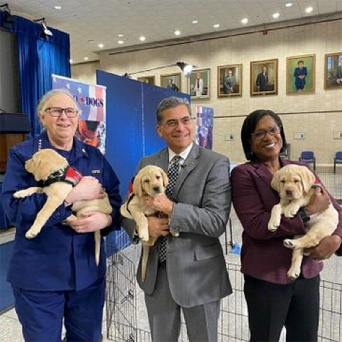 Levine, Becerra and Delphin-Rittmon stand smiling, each holding a puppy.