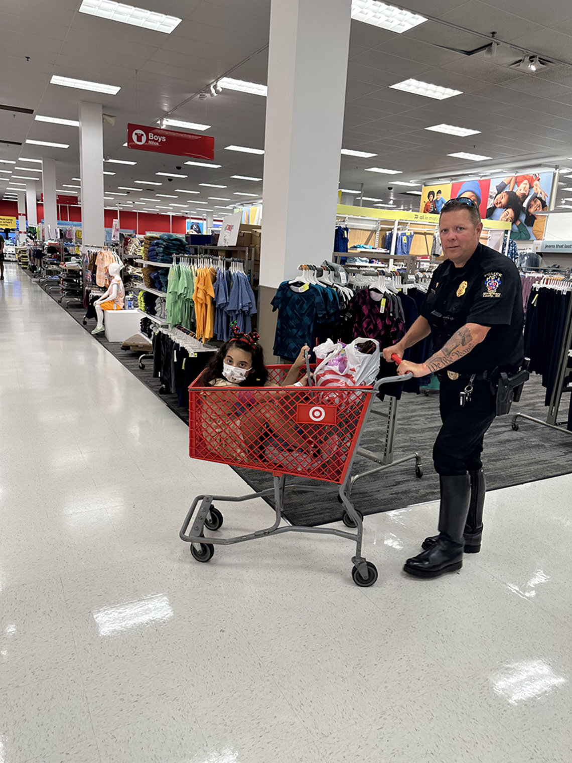 An officer pushes a resident in a grocery cart