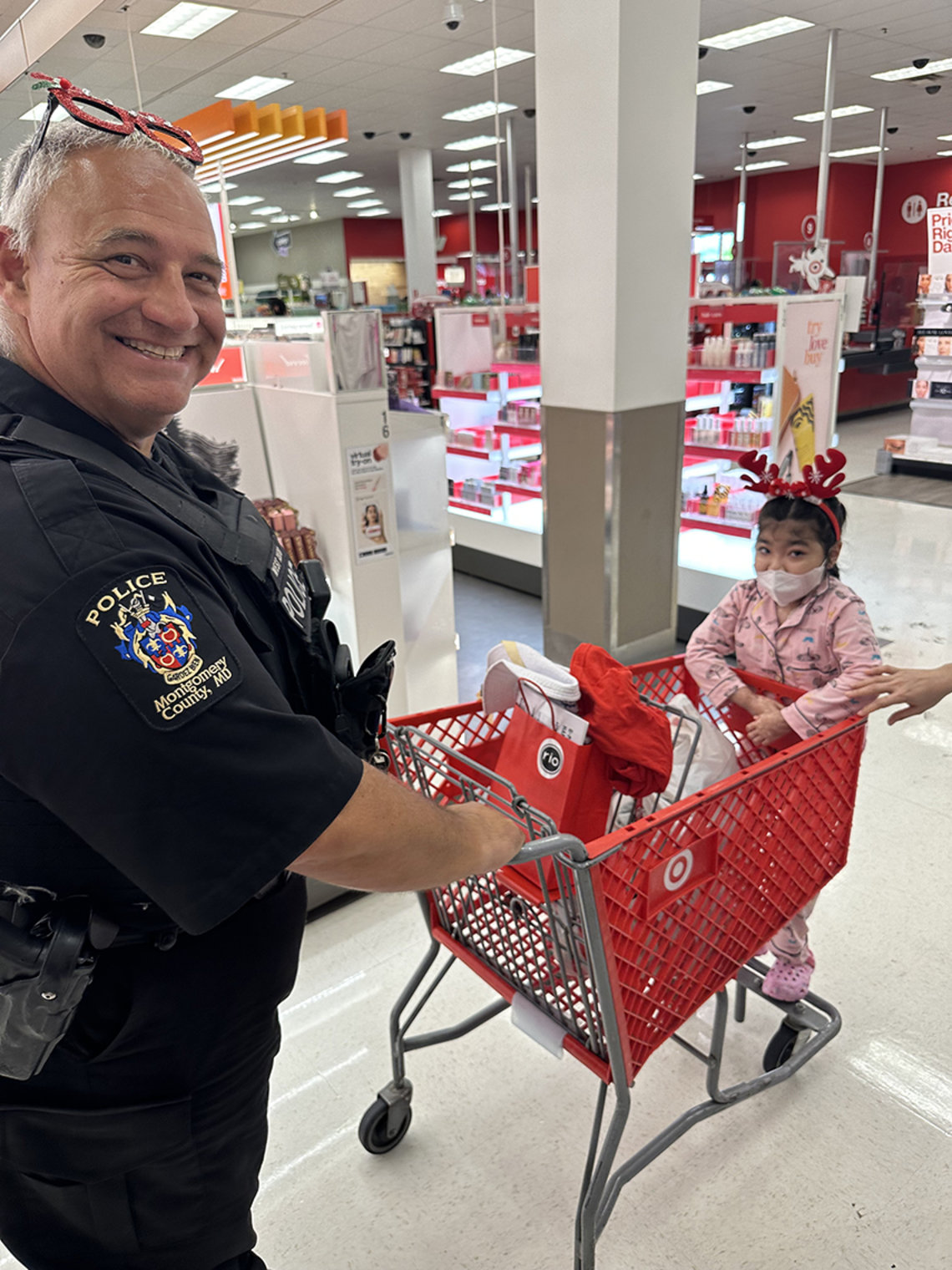 A police officer pushes a child in a grocery cart