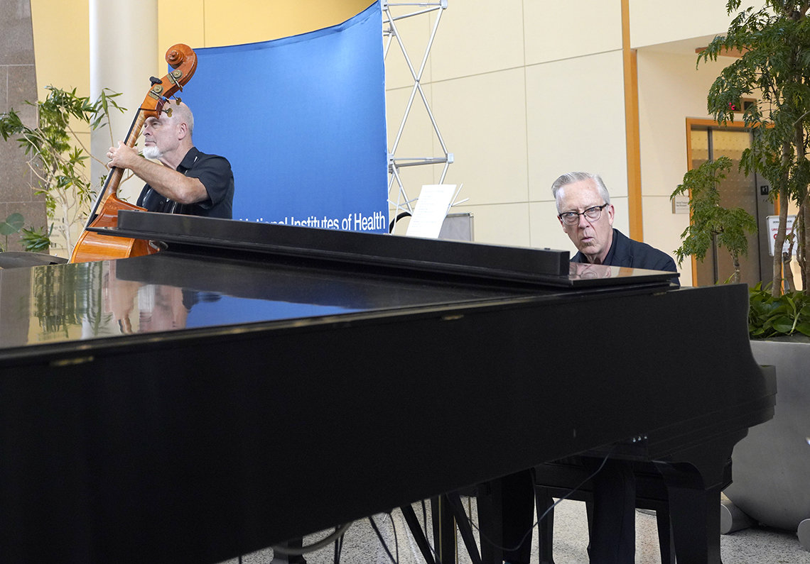 Musicians play with grand piano in forefront