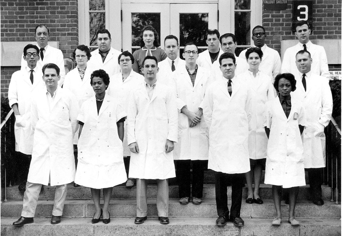 B&W image of large group of individuals in lab coats