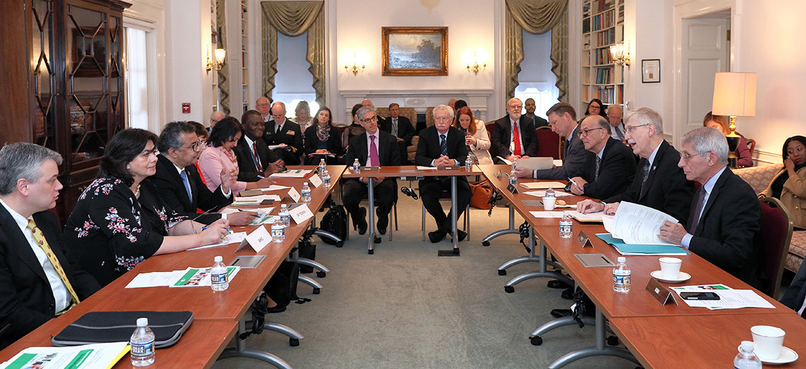 Then-director general of the World Health Organization Dr. Tedros Adhanom Ghebreysus sits at the center of a table, flanked by others.