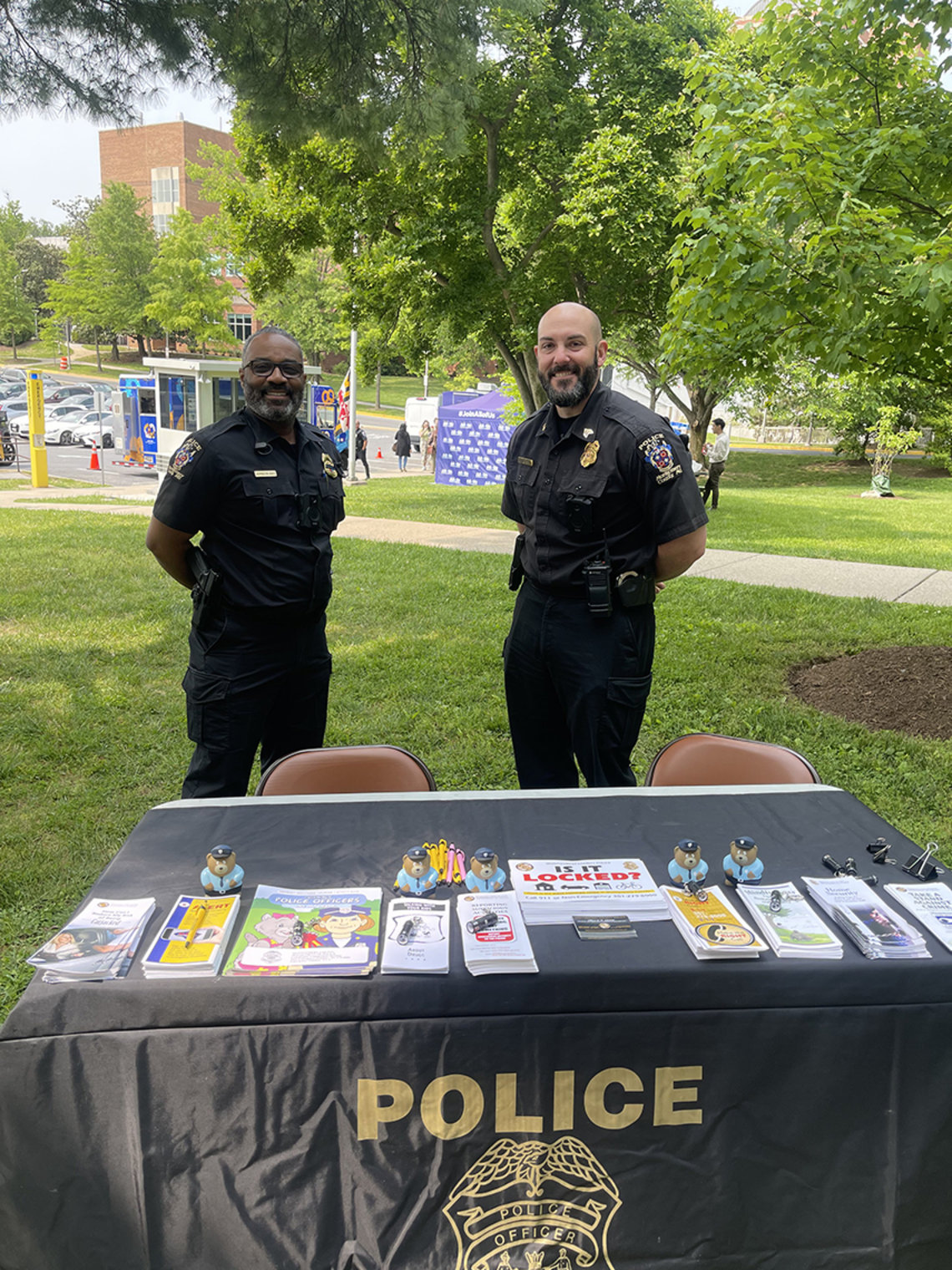 Two officers stand by police table covered in flyers