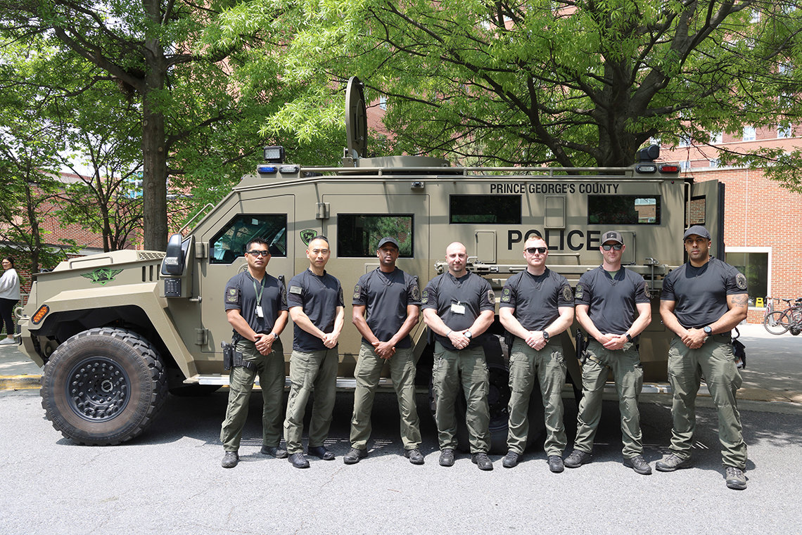 Officers pose in front of a camo van.