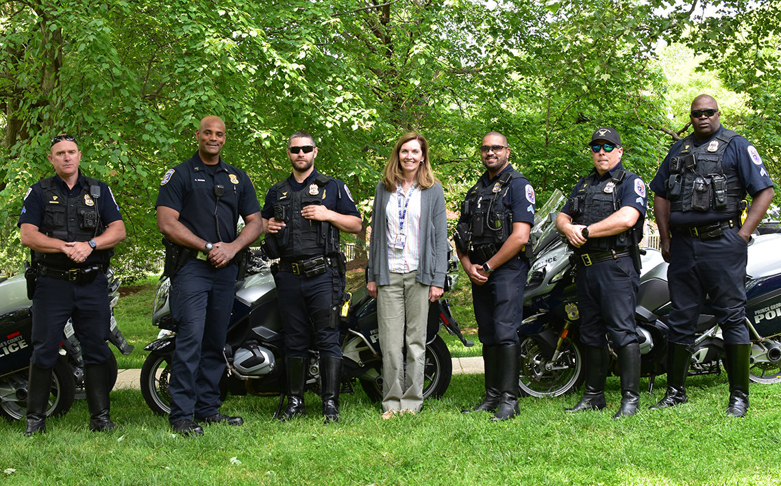 Six officers stand with their motorcycles with a smiling McGowan standing in between them.