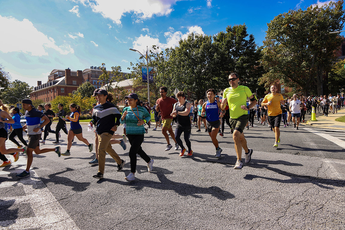 A group of runners and walkers cross Wilson Drive on NIH's campus