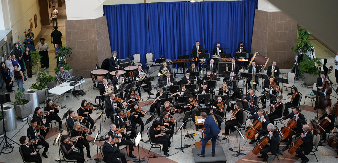 Looking below, from a higher floor, at the full orchestra and conductor