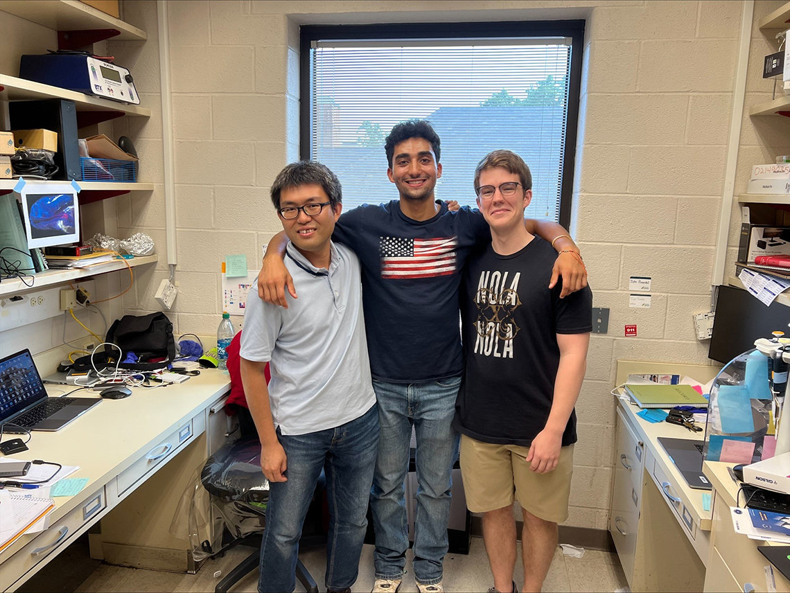 Puthan (middle) stands with his arms around two of his NIH mentors.