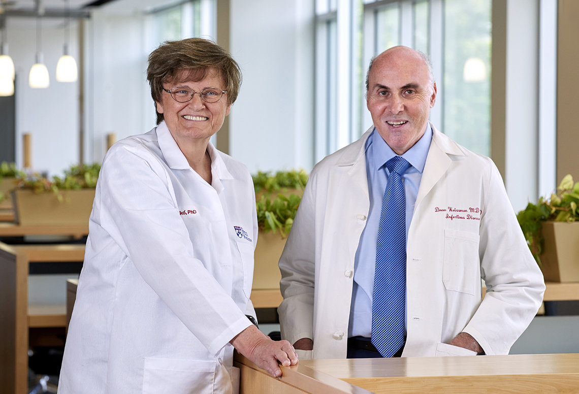 Dr. Karikó and Dr. Weissman wear white lab coats