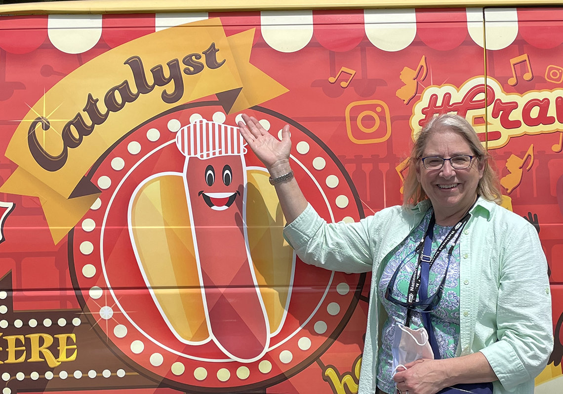 Carter stands in front of the Catalyst Hot Dog logo