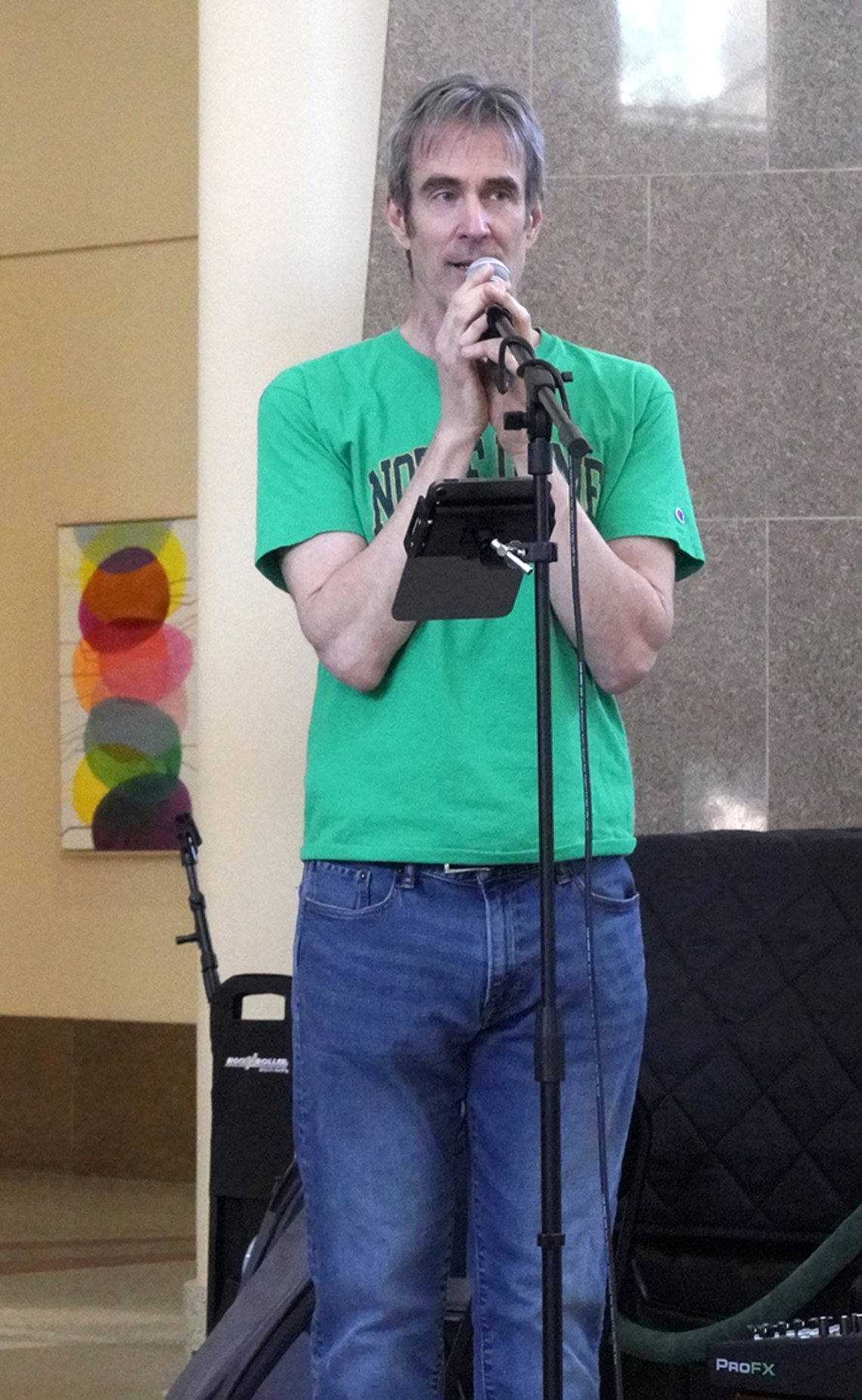 A man in a green t-shirt sings into a microphone.