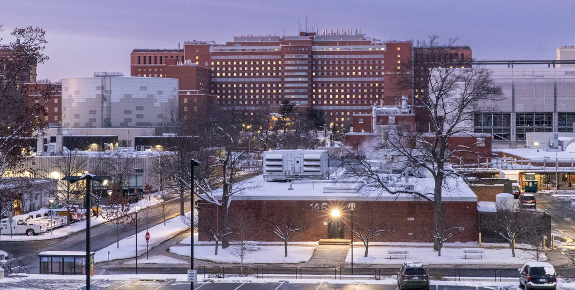 Snow covers the grass and roofs on campus, with the Clinical Center towering in the back