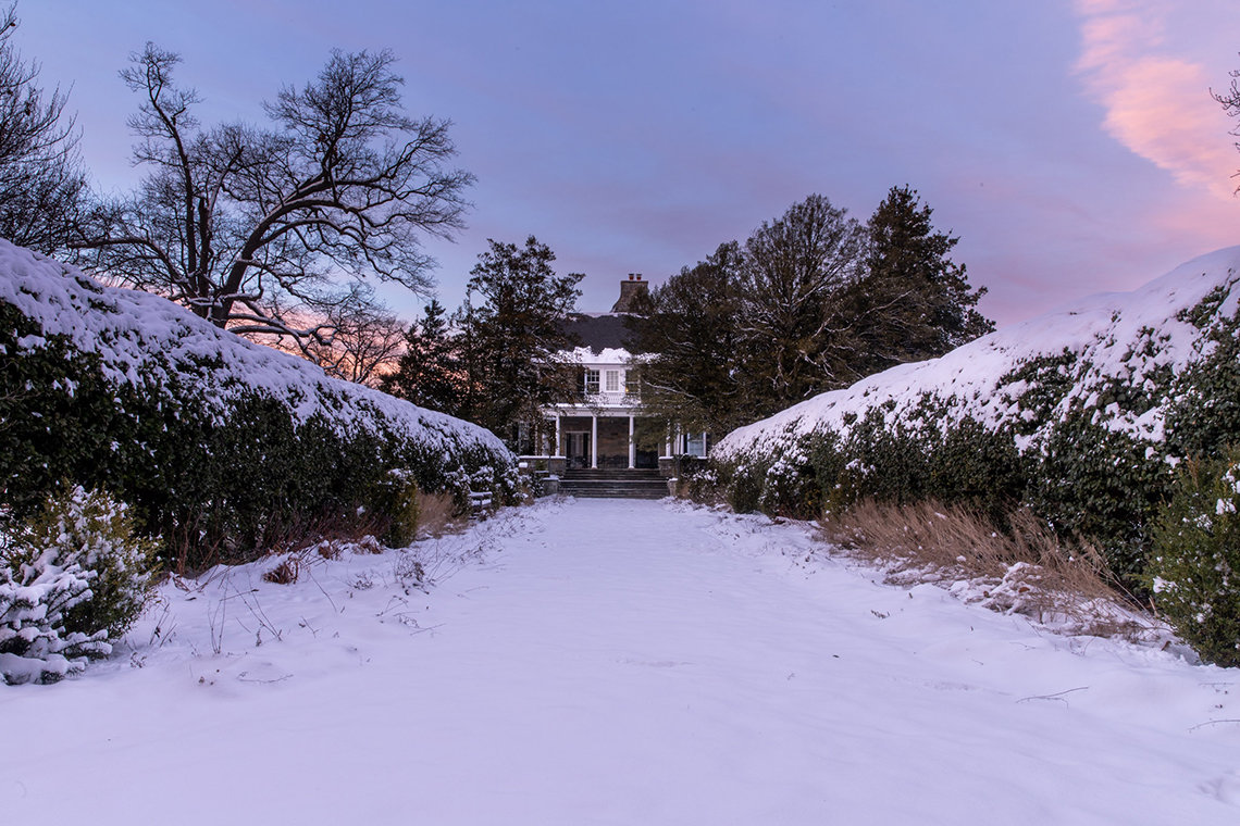 Snow covers the lawn and shrubs on the long path to Stone House