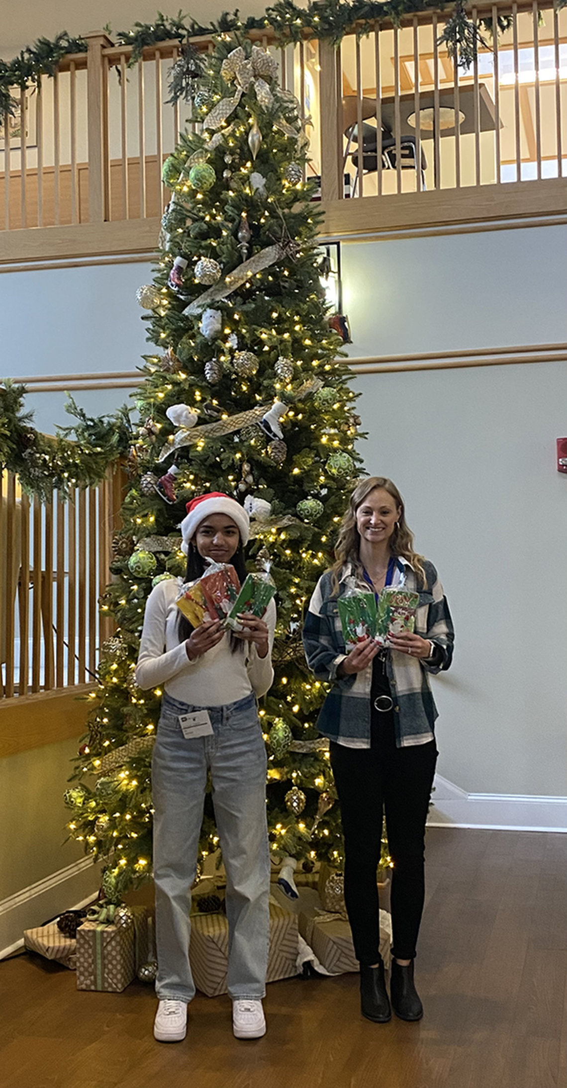 Sampson and Smith stand smiling in front of tall Christmas tree inside the Children's Inn.