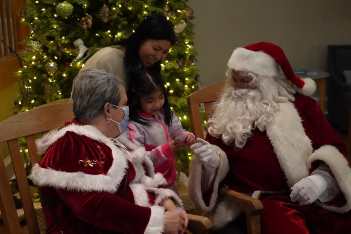 A girl speaks to Santa and Mrs. Claus