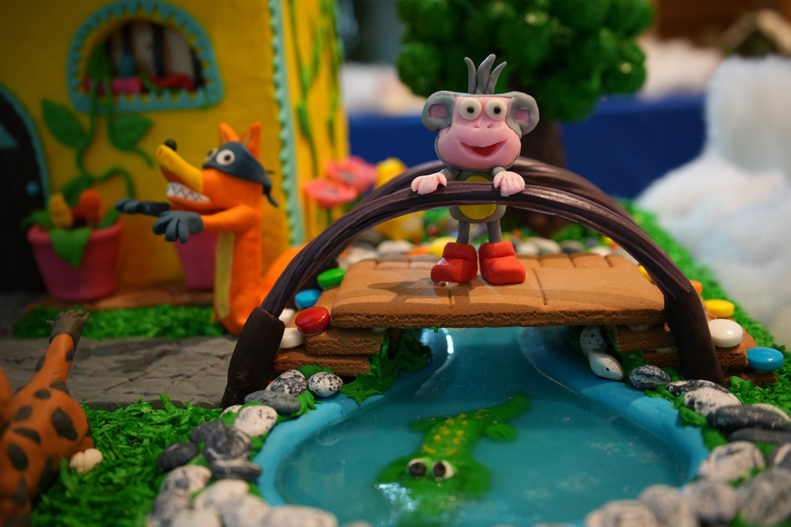 A close-up view of Dora the Explorer, with Boots smiling on a bridge, an alligator in the water below, and Swiper behind