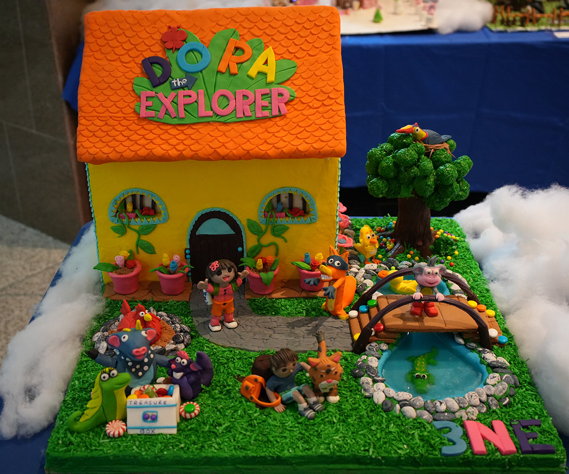 Dora, Boots, Swiper and other characters from Dora the Explorer in front of a colorful gingerbread house