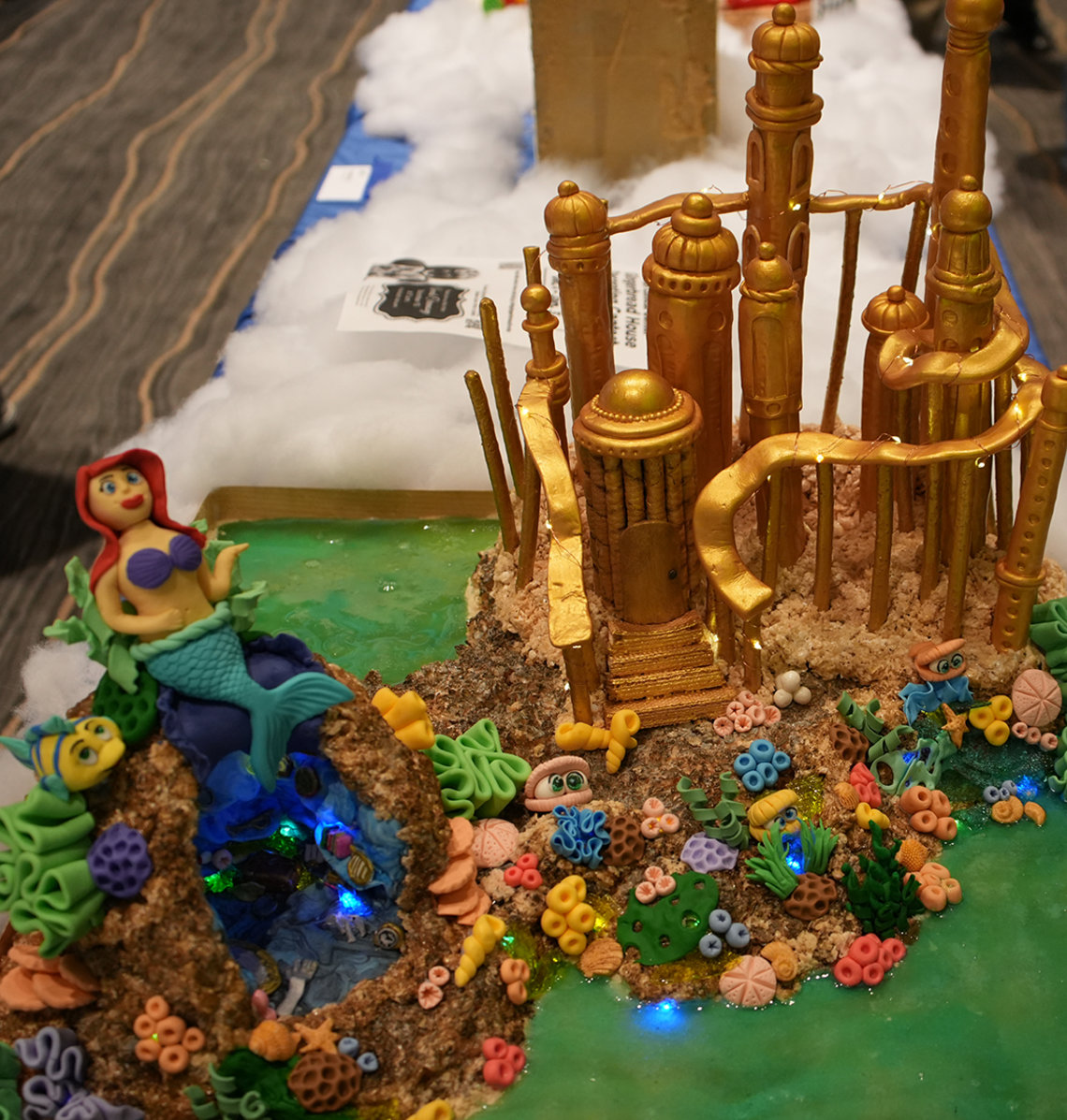 A gold castle with the Little Mermaid next to candy coral and fish
