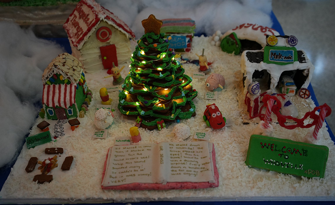A gingerbread house and Christmas tree with lights, an open book, candy cars and little houses of Dr. Seuss's fictional town, Whoville
