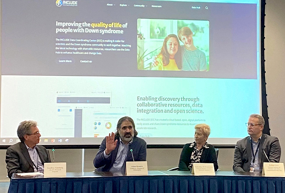 Resnick and three NIH'ers at conference table with a slide behind that reads "Enabling discovery through collaborative resources, data integration and open source"