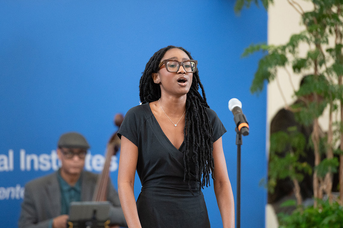 Black woman sings into microphone.