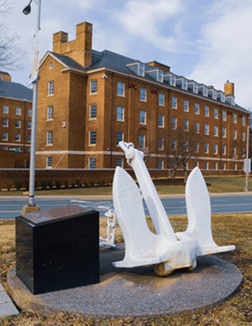 White anchor on platform with plaque with NIH's Building 3 in background.