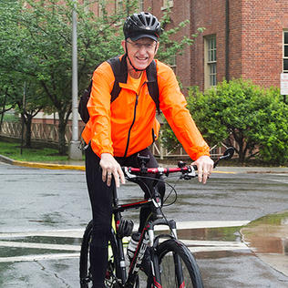 Dr. Francis Collins bicycles onto campus.