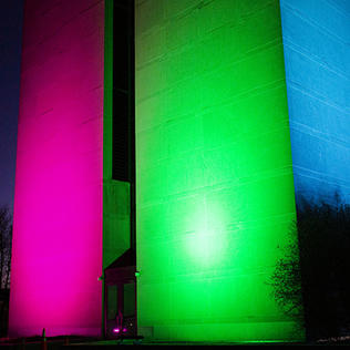 The side of a building on campus is lit up red, green and blue at night. 