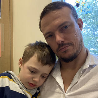 Hampus Flysjo, age 8, rests his head on his father's shoulder at a room in the Clinical Center