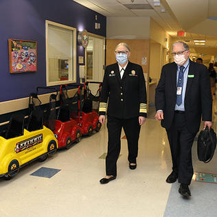 Levine and Tabak stroll through a toy-car-lined hallway