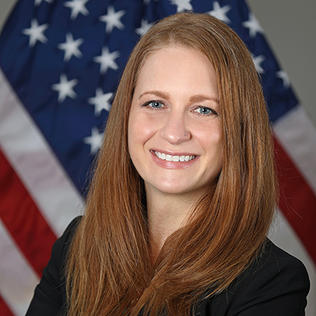 Dr. Tara Schwetz smiles in front of American flag