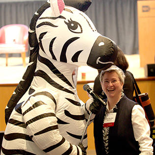 Rutter smiles next to a person in a zebra costume.