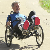 Michael McClellan rides on a tech-assisted three-wheeled recumbent cycle.