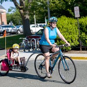 Bicyclist pedals bike towing a child in carrier attachment