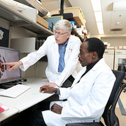 Dr. Collins and Dr. Aimola look at a screen