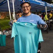 A cyclist wearing a 2009 shirt holds up the 2019 BTWD shirt.  PHOTO: LISA HELFERT