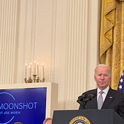 President Joe Biden at a White House East Room podium.