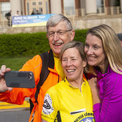In front of Bldg. 1, Collins, in bike-riding gear, takes a selfie with wife Diane Baker and daughter Margaret