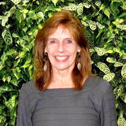 Dr. Lynne Penberthy smiling, green leaves in background