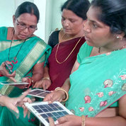 Three women hold small solar panels as a fourth woman looks on