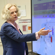 Volkow stands pointing to a slide that shows a red and blue bar graph from clinical trial results.