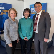 Sen. Capito, Dr. Bertagnolli and Dr. Lei pose together with blue posters behind